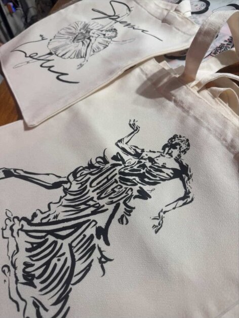 Natural canvas totes printed with ink drawings of a dancer and a classical figure