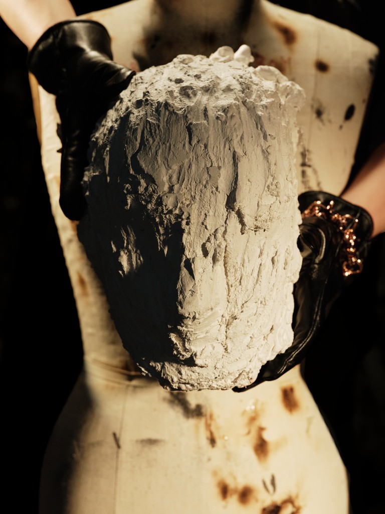 Del Sacro Capo — a plaster head held in black gloves