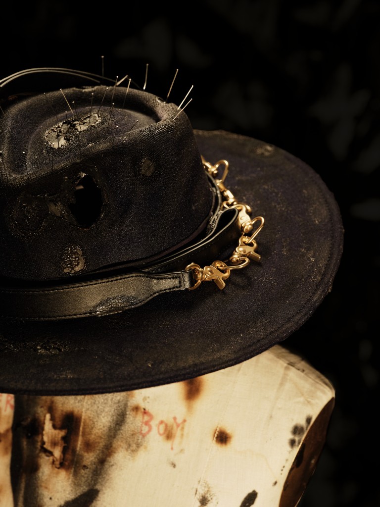 Pileus cocktail — pins, burned holes, and a gold chain on the hat